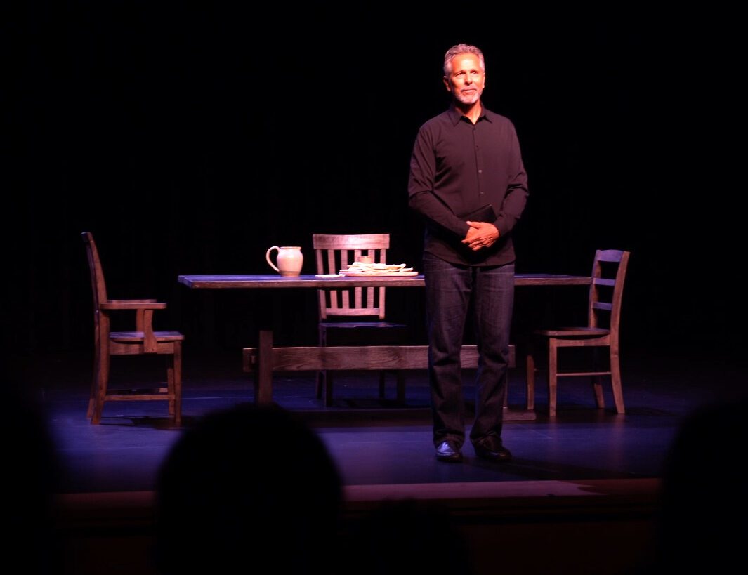 A man standing on stage in front of a table.